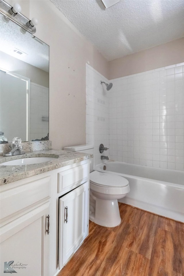 full bath featuring a textured ceiling, wood finished floors, vanity, and toilet