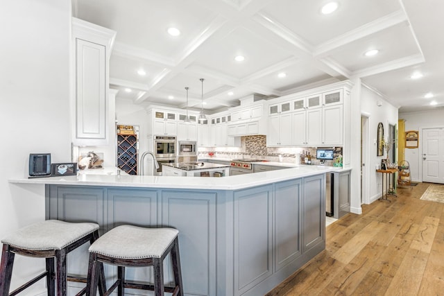 kitchen with beamed ceiling, decorative backsplash, a peninsula, coffered ceiling, and stainless steel appliances