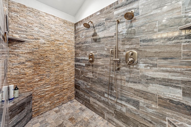 bathroom featuring lofted ceiling and tiled shower