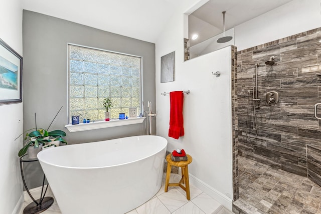 bathroom with a freestanding tub, baseboards, and tiled shower