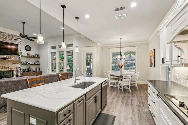 kitchen featuring crown molding, a brick fireplace, visible vents, and a sink