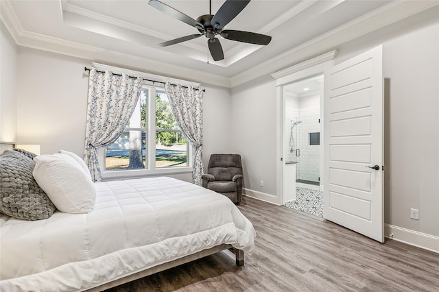 bedroom featuring a tray ceiling, wood finished floors, baseboards, and ornamental molding