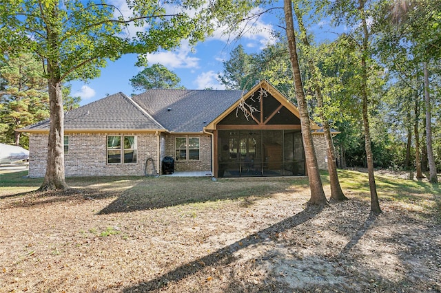 view of front of property with brick siding, a sunroom, and roof with shingles