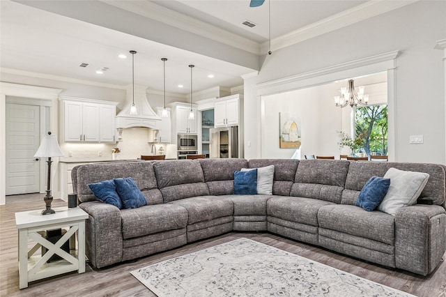 living area with visible vents, light wood-style flooring, recessed lighting, ornamental molding, and a chandelier