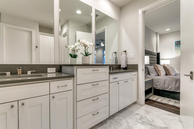 ensuite bathroom featuring two vanities, recessed lighting, marble finish floor, ensuite bath, and a sink