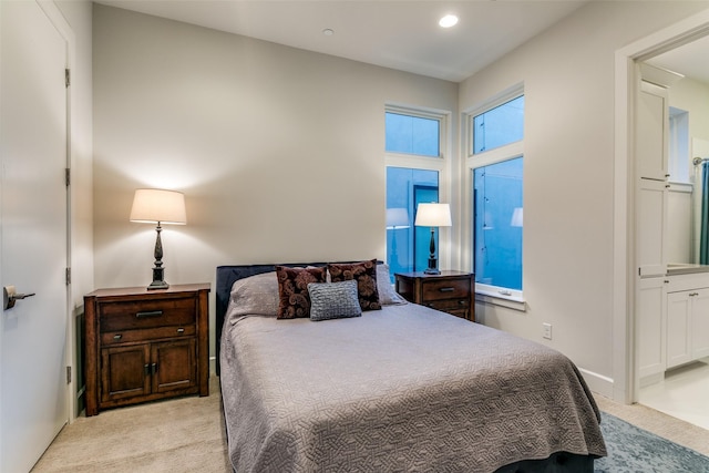 bedroom with recessed lighting, light carpet, and ensuite bathroom