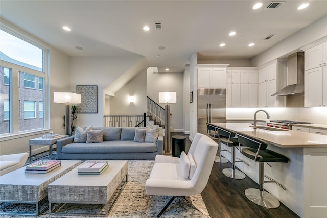 living room with recessed lighting, visible vents, dark wood finished floors, and stairway