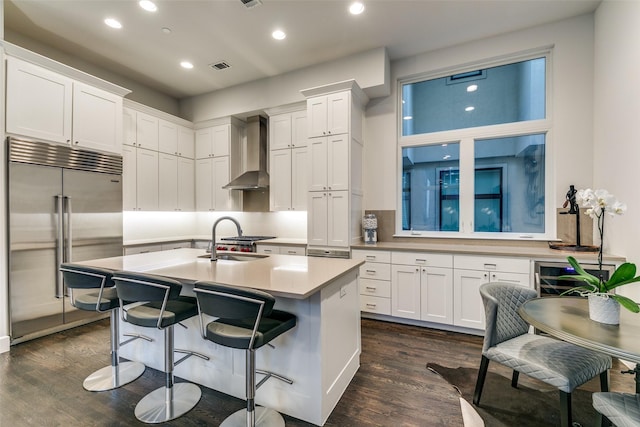 kitchen with dark wood-style floors, white cabinetry, wall chimney exhaust hood, and built in fridge