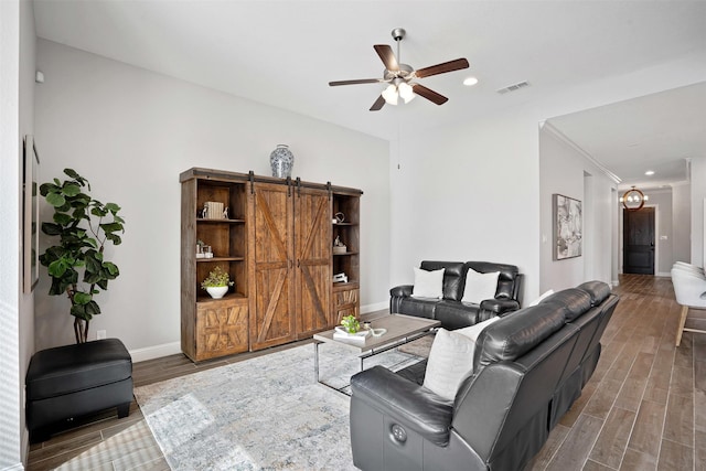 living area with a barn door, baseboards, visible vents, and wood finished floors