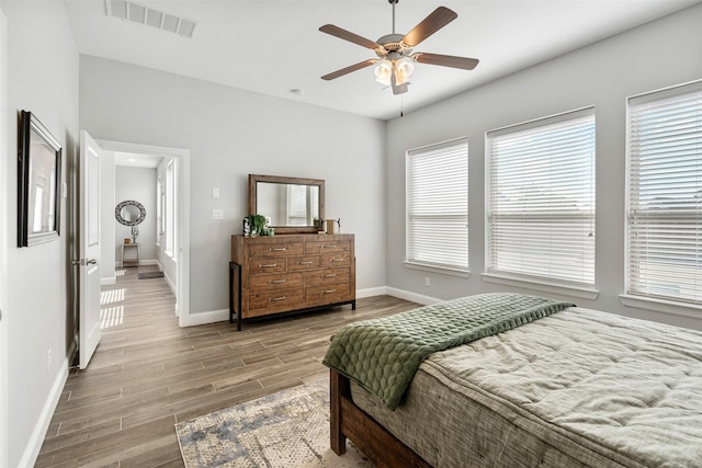 bedroom with visible vents, baseboards, wood finished floors, and a ceiling fan