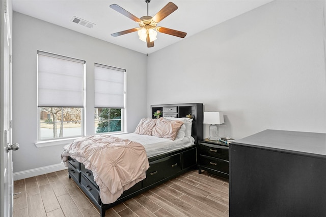 bedroom with wood finish floors, visible vents, baseboards, and ceiling fan