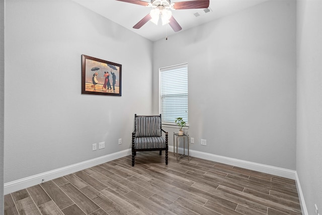 living area with a ceiling fan, wood finished floors, visible vents, and baseboards