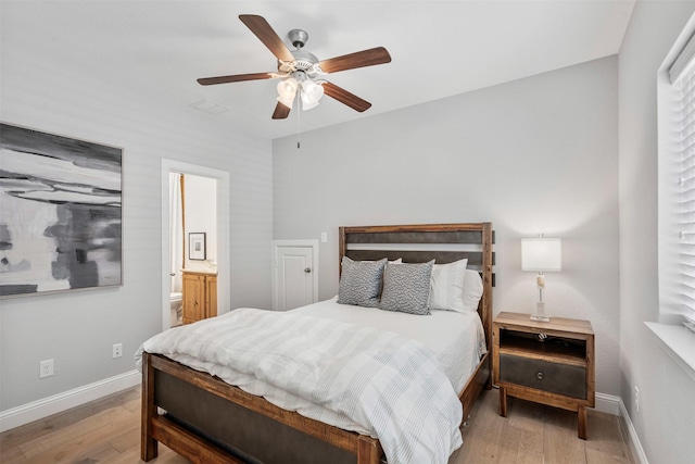 bedroom featuring a ceiling fan, ensuite bathroom, baseboards, and wood finished floors