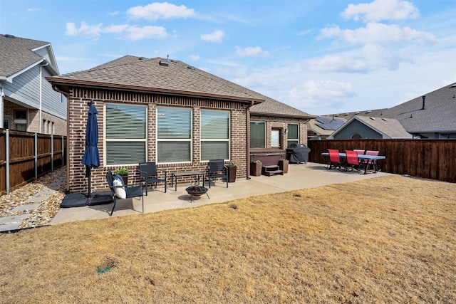 back of property with brick siding, a patio area, a shingled roof, and a fenced backyard