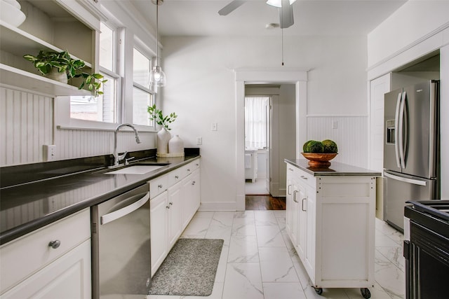 kitchen featuring marble finish floor, a sink, dark countertops, appliances with stainless steel finishes, and a healthy amount of sunlight