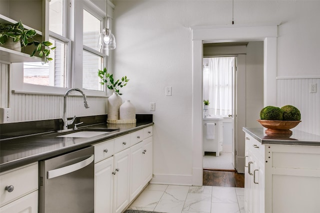 kitchen featuring marble finish floor, a sink, stainless steel countertops, white cabinets, and dishwasher