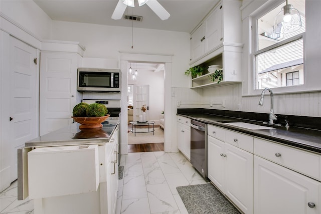 kitchen featuring dark countertops, visible vents, appliances with stainless steel finishes, marble finish floor, and a sink