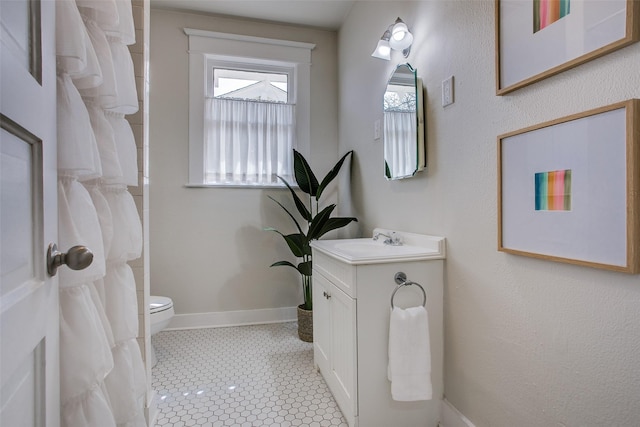 bathroom featuring tile patterned flooring, toilet, vanity, and baseboards