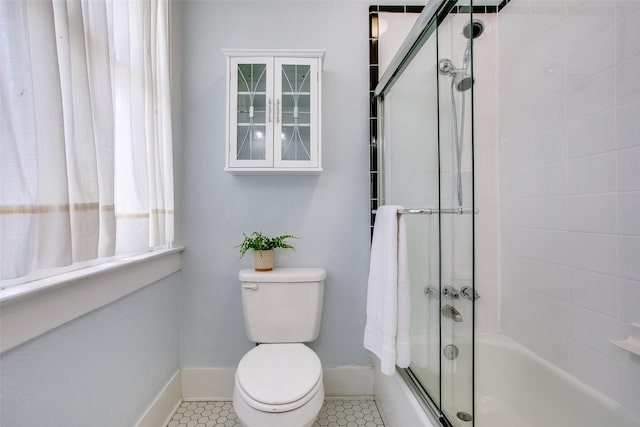 full bath with tile patterned floors, baseboards, bath / shower combo with glass door, and toilet