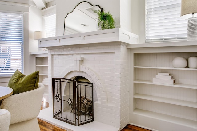 interior details featuring visible vents, a brick fireplace, and wood finished floors