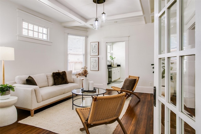 living area with beam ceiling, coffered ceiling, baseboards, and wood finished floors