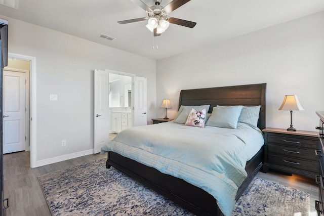 bedroom featuring visible vents, ensuite bath, baseboards, and wood finished floors