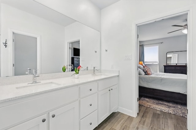 bathroom featuring a ceiling fan, wood finished floors, ensuite bathroom, and a sink