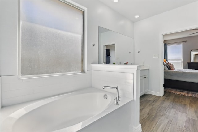 ensuite bathroom with vanity, wood finished floors, recessed lighting, ensuite bathroom, and a garden tub