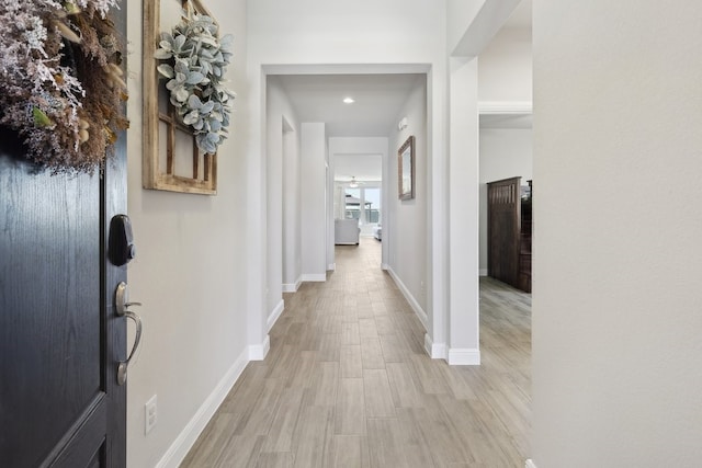 hall with baseboards and light wood finished floors