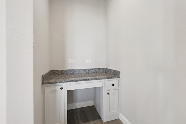 interior space with dark wood-style floors, built in study area, and baseboards