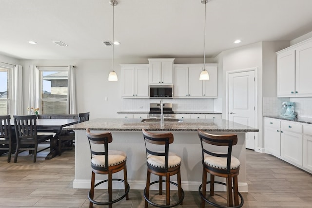 kitchen featuring a center island with sink, appliances with stainless steel finishes, a breakfast bar, and a sink