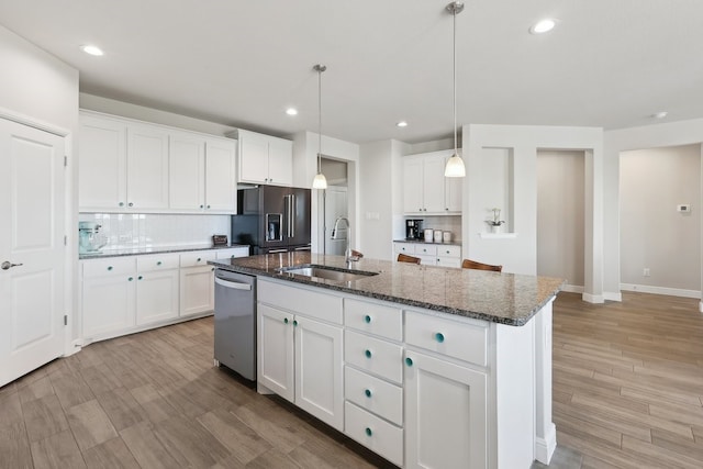 kitchen with a center island with sink, decorative backsplash, high quality fridge, stainless steel dishwasher, and a sink