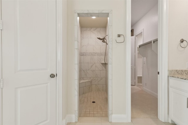 full bath with vanity, baseboards, and a tile shower