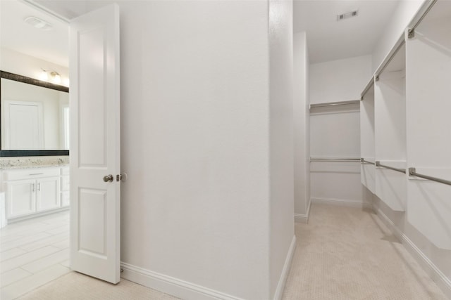 walk in closet featuring visible vents and light carpet