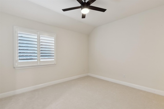 empty room with light carpet, baseboards, ceiling fan, and vaulted ceiling