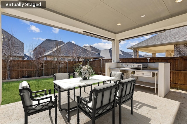 view of patio with outdoor dining space, a sink, a fenced backyard, a grill, and an outdoor kitchen