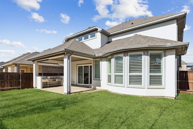 back of house featuring stucco siding, a lawn, a patio, fence, and a shingled roof