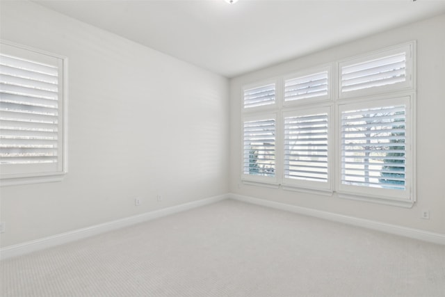 carpeted empty room featuring baseboards