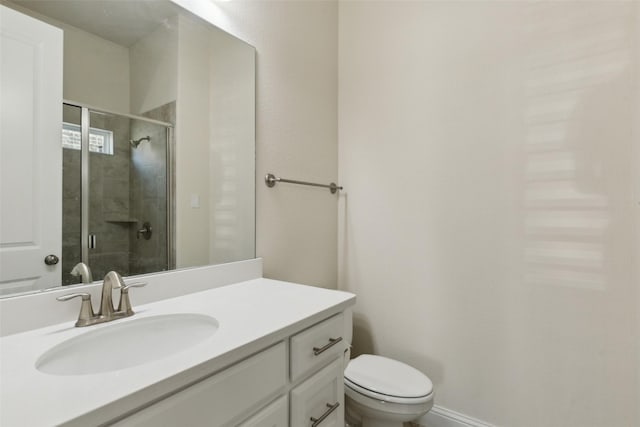 bathroom with toilet, a stall shower, vanity, and baseboards