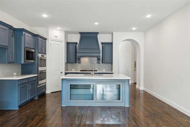 kitchen with premium range hood, stainless steel appliances, arched walkways, light countertops, and dark wood-style flooring