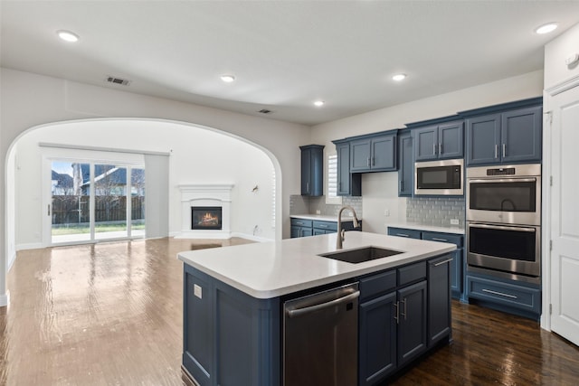 kitchen with a sink, stainless steel appliances, light countertops, tasteful backsplash, and open floor plan