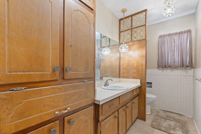 bathroom featuring tile walls, toilet, vanity, tile patterned floors, and a textured ceiling