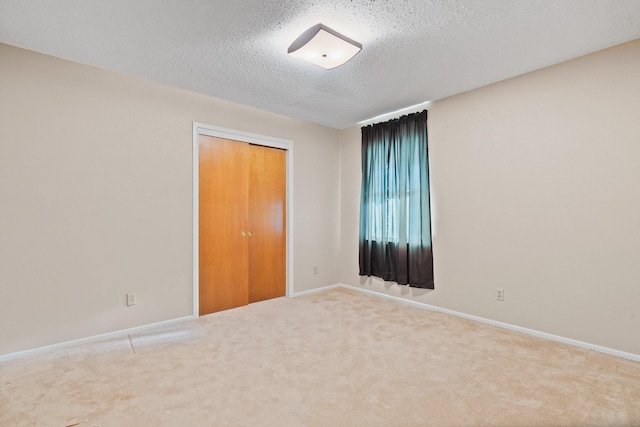 unfurnished room featuring carpet, baseboards, and a textured ceiling