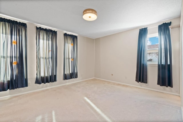 unfurnished room featuring carpet flooring, baseboards, and a textured ceiling