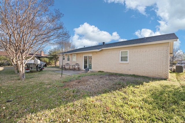 back of property featuring a patio, a yard, brick siding, and central AC