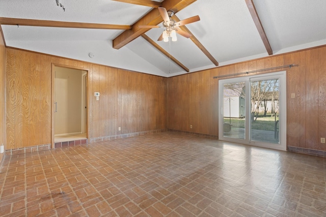 empty room featuring lofted ceiling with beams, wooden walls, brick floor, and ceiling fan