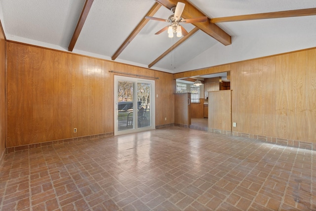 unfurnished living room with wood walls, brick floor, lofted ceiling with beams, and a ceiling fan