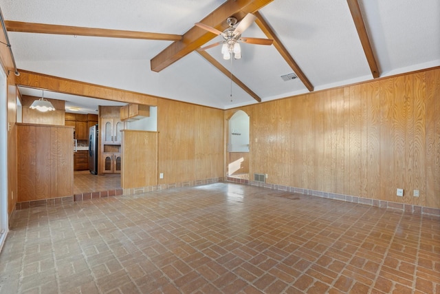 spare room featuring visible vents, arched walkways, wood walls, and a ceiling fan