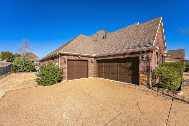 view of side of home with an attached garage, brick siding, and driveway