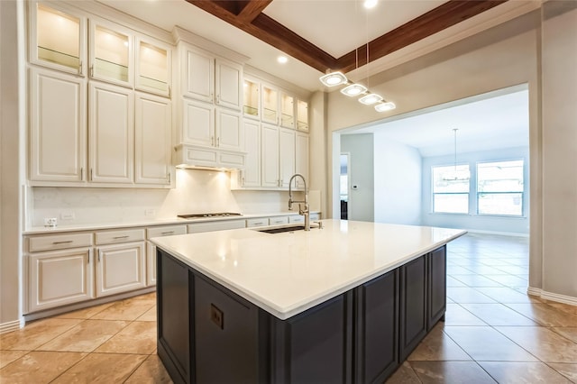 kitchen with a sink, light tile patterned flooring, light countertops, glass insert cabinets, and hanging light fixtures